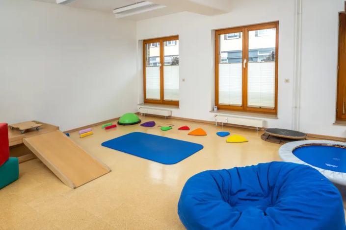 Blick in einen Übungsraum mit diversen bunten Matten und Gegenständen